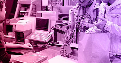 Image of man at checkout serving customers buying a pineapple