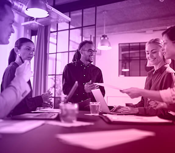 Image of business people standing around a desk brainstorming and chatting